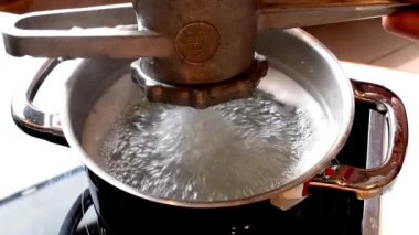  Sıcak suda bir makineyle Swabian spaetzle 'ına basmak