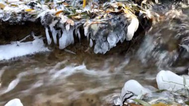 Almanya 'da kış mevsiminde güneş ışınları ve buz saçakları olan vahşi dere, buz saçaklarıyla çağlayan çağlayanın yakınına doğru çekiliyor.
