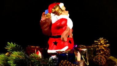 Yanan mumlu çelenk ve dönen masada Noel Baba.