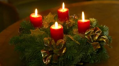 Yanan mumlar ve dönen bir masada Noel beşiği olan yeni çelenk.