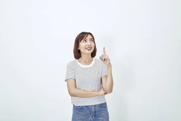 カジュアルなTシャツと青いジーンズで魅力的なアジアの女性の笑顔の肖像画は 指の上の白い背景を指しています スペースのコピー — ストック写真