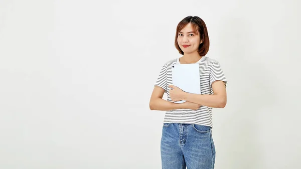 Tシャツとジーンズを身に着けている短い茶色の髪と魅力的な若いアジアの女性従業員は笑顔と白い背景コピースペースに立ってデジタルタブレットを保持 — ストック写真