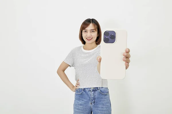 Tシャツの若いアジアの女性とスマートフォンを示す青いジーンズ — ストック写真
