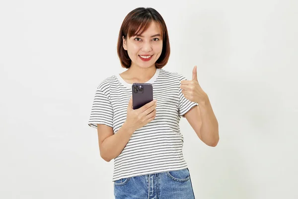 携帯電話を持っている若いアジアの女性と白い背景にスマートフォンで立って プロモーションテキストを示す 指の空のコピースペースを指す — ストック写真
