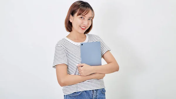若いビジネスアジアの女性従業員とともに短い茶色の髪を身に着けていますTシャツとジーンズ笑顔とホワイトバックグラウンドコピースペースに立ってデジタルタブレットを保持 — ストック写真