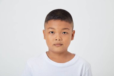 Beyaz tişörtlü yakışıklı Asyalı çocuk izole edilmiş bir stüdyoda beyaz arka planda kameraya bakıyor.
