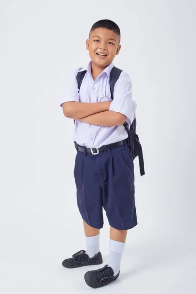 stock image A young Asian cute boy standing in a Thai school uniform with a backpack bag and book on a white background banner. Back to school