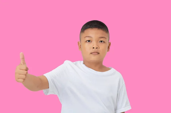 可愛いです笑顔アジアの男の子で平たい白いTシャツでカメラを見て隔離されたスタジオライトピンク色の背景 — ストック写真