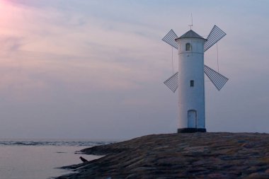 Yel değirmeni şeklinde bir deniz fenerinin üzerinde güzel bir gün batımı, Swinoujscie, Polonya