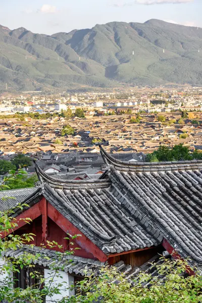 타운의 주택의 중국어 지붕의 아름다운 산들은 배경에서 있습니다 Lijiang는 아시아의 로열티 프리 스톡 이미지