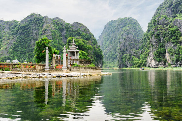 Awesome view of natural karst towers reflected in water of the Ngo Dong River at the Tam Coc portion, Ninh Binh Province, Vietnam. The Tam Coc is a popular tourist attraction in Asia.