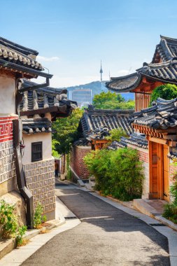 Güney Kore, Seul 'deki Bukchon Hanok Köyü' nün sıcacık, eski ve geleneksel Kore evlerinin güzel manzarası. Namsan Dağı 'ndaki Seul Kulesi mavi arka planda görünüyor..
