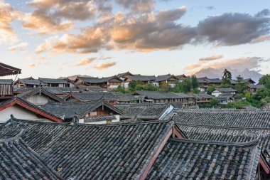 Çin 'in Lijiang şehrindeki otantik evlerin geleneksel Çin siyah kiremit çatıları. Renkli günbatımı gökyüzünün muhteşem manzarası. Lijiang Asya 'nın popüler bir turizm merkezidir..