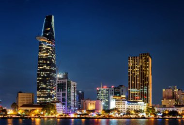 Ho Chi Minh City silueti ve Saigon Nehri. Şehir merkezindeki gökdelenin ve diğer modern binaların güzel gece manzarası. Ho Chi Minh Şehri Vietnam 'ın popüler bir turizm merkezidir. Manzaralı şehir manzarası
