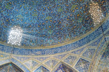 İsfahan, İran - 24 Ekim 2018: Seyyid Camii 'nin içindeki taş oyma pencere ve ışık oyununun inanılmaz görüntüsü. Renkli mozaik ve kaligrafik yazıtlarla kaplı duvarlar. İslam mimarisi.