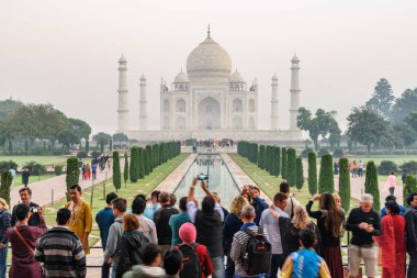 Agra, Hindistan - 8 Kasım 2018: Tac Mahal 'in fotoğraflarını çeken turistler. Sabah vakti beyaz mermer mozolenin harika manzarası..