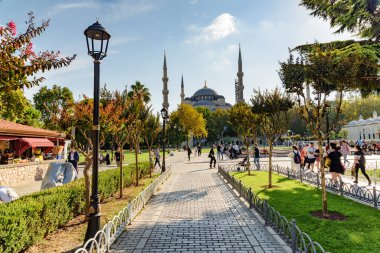 Yeşil bahçelerin arasında Sultan Ahmed Camii 'nin (Mavi Cami) muhteşem manzarası. Turistler ve halk dinleniyor ve manzaralı şehir parkı boyunca yürüyorlar..