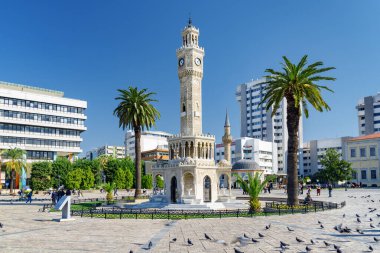 İzmir, Türkiye - 26 Ekim 2021: İzmir Saat Kulesi 'nin Konak Meydanı' nın ortasındaki manzarası ve güvercin sürüsü. Kule liman şehrinin simgesidir..