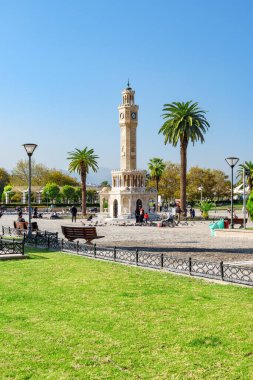 İzmir, Türkiye - 26 Ekim 2021: Konak Meydanı 'nın ortasındaki İzmir Saat Kulesi manzarası. Turistler ve halk dinleniyor ve meydanda yürüyorlar. Kule liman şehrinin simgesidir..