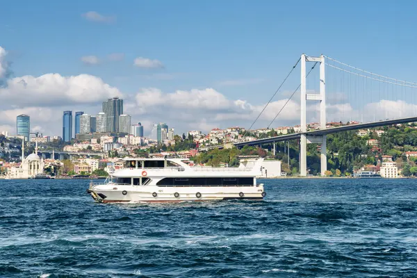 Turist teknesi Boğaz 'ı geçiyor. Avrupa 'yı Asya' ya bağlayan Boğaziçi Köprüsü 'nün (15 Temmuz Şehitler Köprüsü) muhteşem manzarası. İnanılmaz İstanbul silüeti.