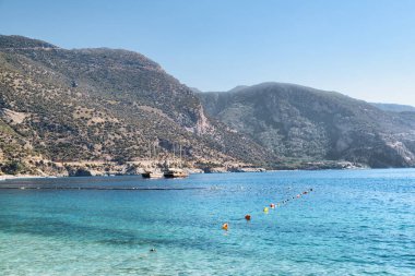Türkiye 'nin Oludeniz Sahili' nden Akdeniz 'in harika berrak sularının manzarası. Manzaralı dağlar arka planda görünür. Oludeniz, Türkiye 'de popüler bir turizm merkezi..