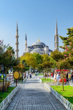 Yeşil bahçelerin arasında Sultan Ahmed Camii 'nin (Mavi Cami) muhteşem manzarası. Turistler ve halk dinleniyor ve manzaralı şehir parkı boyunca yürüyorlar..