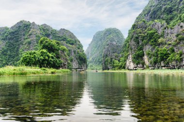 Tam Coc, Ninh Binh Eyaleti, Vietnam 'daki Ngo Dong Nehri' nin sularına yansıyan doğal karst kulelerinin muhteşem manzarası. Tam Coc Asya 'da popüler bir turistik merkezdir..