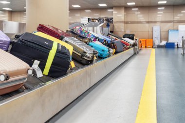 Suitcases of different colors on luggage conveyor belt at arrival area of passenger terminal in airport. Baggage carousel. clipart