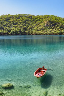 Oludeniz, Türkiye 'deki Blue Lagoon kıyısında demirlemiş muhteşem manzaralı kırmızı tekne manzarası. Amazing Blue Lagoon, Türkiye 'de ulusal bir doğa rezervi ve dünyanın popüler turistik merkezlerinden biridir..