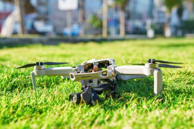 İnsansız hava aracı kazası. Yeşil çimlerde hasar görmüş kuadkopter. Şehir parkında bozuk bir dron..