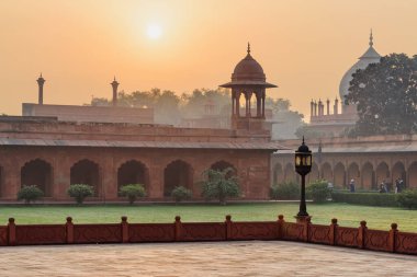 Hindistan 'ın Agra kentindeki Taj Mahal kompleksinde gün doğumunun inanılmaz manzarası. Kemerli güzel kırmızı kumtaşı duvarlar. Muhteşem Babür mimarisi. Tac Mahal Güney Asya 'nın popüler bir turistik merkezidir..