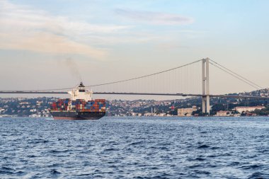 İstanbul, Türkiye - 18 Eylül 2021: Konteyner gemisi Boğaz 'ı geçiyor. Avrupa 'yı Asya' ya bağlayan Boğaziçi Köprüsü 'nün (15 Temmuz Şehitler Köprüsü) muhteşem manzarası.