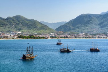 Türkiye 'nin Alanya kıyısındaki Akdeniz' deki turist gemileri ve teknelerinin muhteşem manzarası. Gemiler korsan olarak süslenmiş. Alanya Türkiye 'de popüler bir turizm beldesi.