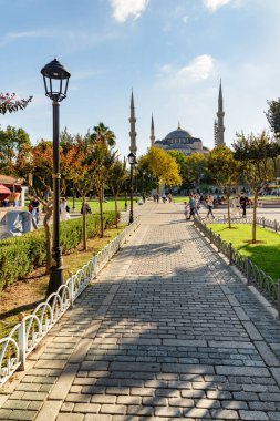 Yeşil bahçelerin arasında Sultan Ahmed Camii 'nin (Mavi Cami) muhteşem manzarası. Turistler ve halk dinleniyor ve manzaralı şehir parkı boyunca yürüyorlar..