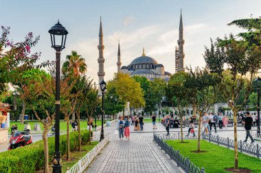 Yeşil bahçelerin arasında Sultan Ahmed Camii 'nin (Mavi Cami) muhteşem manzarası. Turistler ve halk dinleniyor ve manzaralı şehir parkı boyunca yürüyorlar..