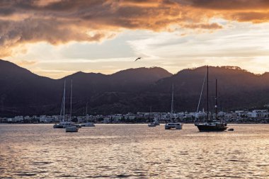 Türkiye 'nin Marmaris Limanı' ndan geçen yatların günbatımı manzarası. Liman kenti, Türk Rivierası 'nda popüler bir turizm beldesi..