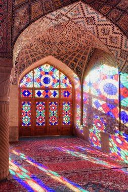 Shiraz, Iran - 31 October, 2018: Awesome morning sunlight reflected through colorful stained glass windows on the wall and the floor of prayer hall at the Nasir al-Mulk Mosque (Pink Mosque). clipart