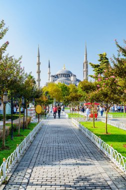 Yeşil bahçelerin arasında Sultan Ahmed Camii 'nin (Mavi Cami) muhteşem manzarası. Turistler ve halk dinleniyor ve manzaralı şehir parkı boyunca yürüyorlar..