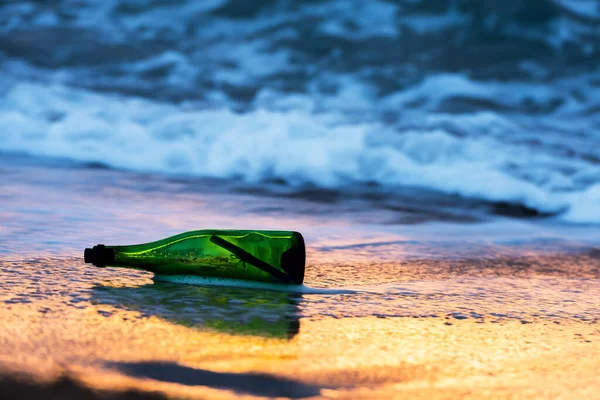 Green glass bottle with paper message on the seashore of tropical beach. Shipwreck in the sea. Plea for help. Save Our Souls SOS concept