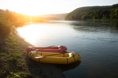 Turuncu ve sarı paketler gündoğumu nehrinde kürek çeken lastik botlar. Paketleme. Etkin yaşam konsepti