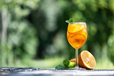 Aperol Spritz Aperitivo yaz kokteyli. Orijinal bardakta, portakallı ve ahşap masa arkasında nane dallı. Yiyecek ve içecek fotoğrafçılığı