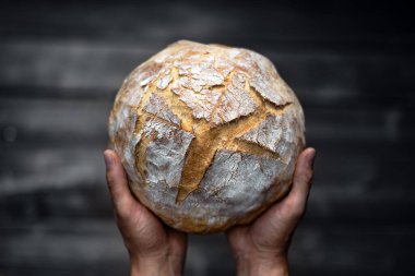 Geleneksel mayalanmış hamur ekmeği fırıncının ellerinde, ahşap bir masada. Sağlıklı yemek fotoğrafçılığı
