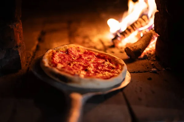 意大利披萨辣香肠是在烧木柴的烤箱里烹调的 比萨饼和意大利面放在火热的烤箱里 食品摄影 — 图库照片