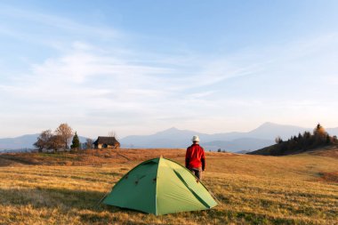 Dağ kampında çadırının yakınında kırmızı ceketli bir turist. Ukrayna Karpatları, Ukrayna