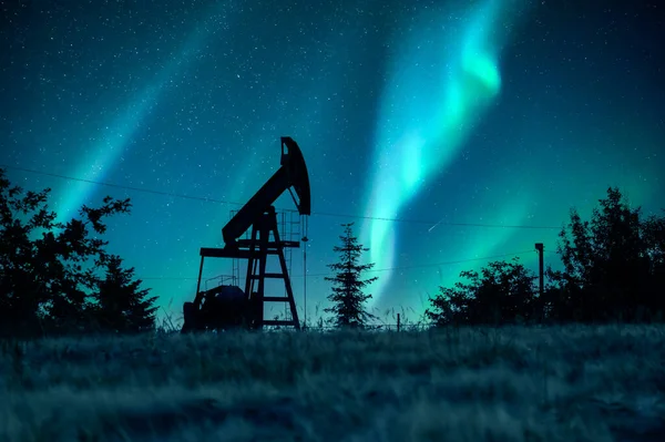 Pump jack silhouette on night sky with Northern light. Oil pump against incredible nirght sky with Aurora Borealis. Industrial concept