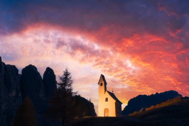 Incredible view on small iIlluminated chapel - Kapelle Ciapela on Gardena Pass, Italian Dolomites mountains. Colorful sunset in Dolomite Alps, Italy. Landscape photography