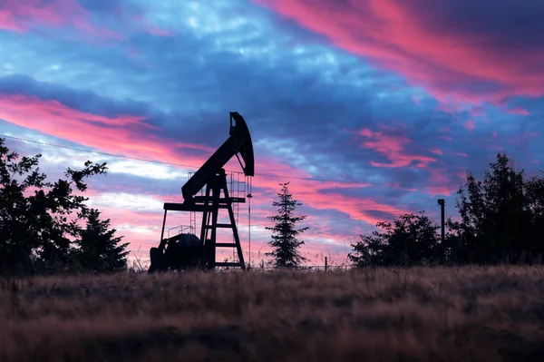 夕方のフィールドにジャックシルエットをポンプ 信じられないほどの紫色の日没の空に対する油ポンプ 産業コンセプト — ストック写真