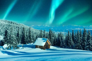 Dağlık bir kış manzarası, kır kulübesi ve çayırda karla kaplı çam ağaçları. Aurora borealis. Kuzey ışıkları kış ormanında. Noel tatili ve kış tatili konsepti