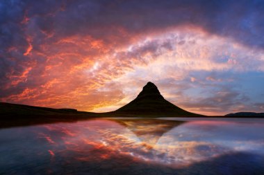 Kirkjufell dağının üzerinde gün batımı İzlanda 'daki bir dağ gölünün berrak sularına yansıyor. Peyzaj fotoğrafçılığı