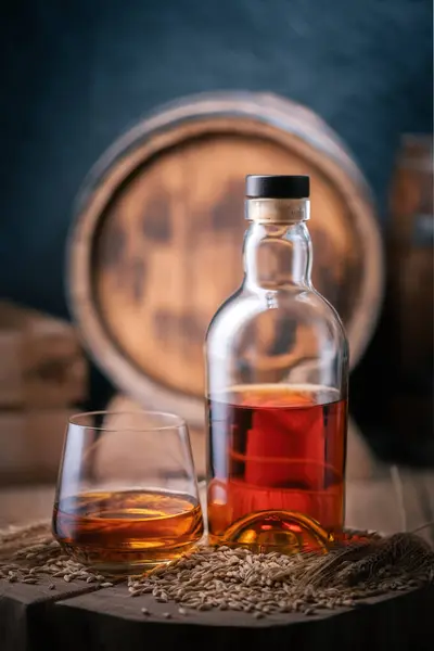 Glass Whiskey Bottle Wooden Board Oak Barrel Background Barley Grains — Stock Photo, Image